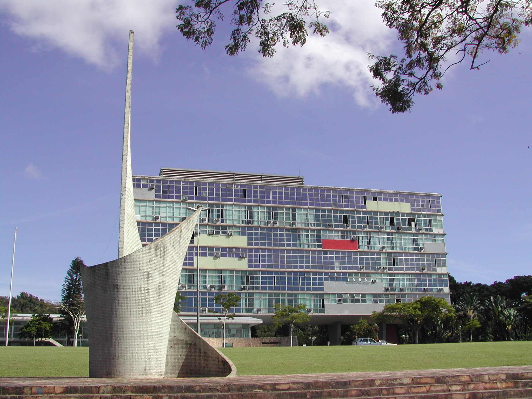 Em primeiro plano o monumento em formato de folha concêntrica e no fundo a faixada do prédio.