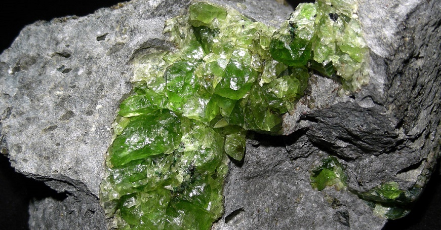 maça cinza claro (rocha), com cristais de coloração verde limão (mineral peridoto)