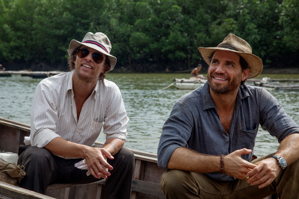 Dois homens em um barco, num rio em uma floresta.