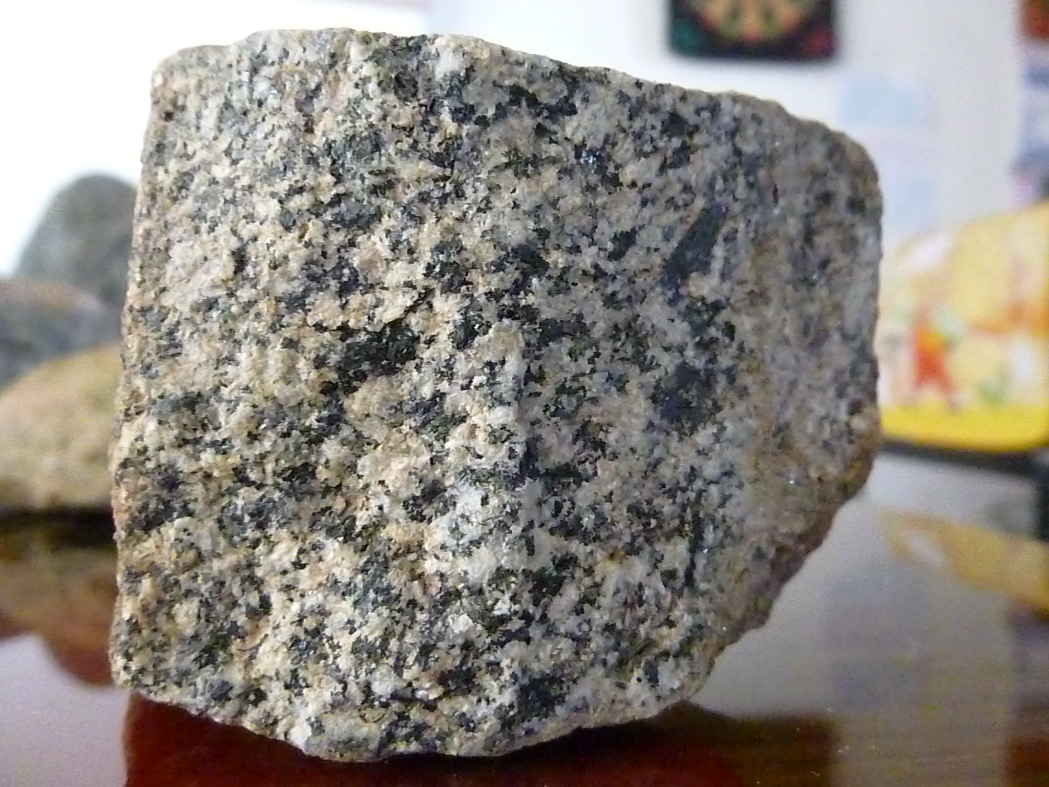 pedaço de granito branco com cristais pretos em cima de uma mesa