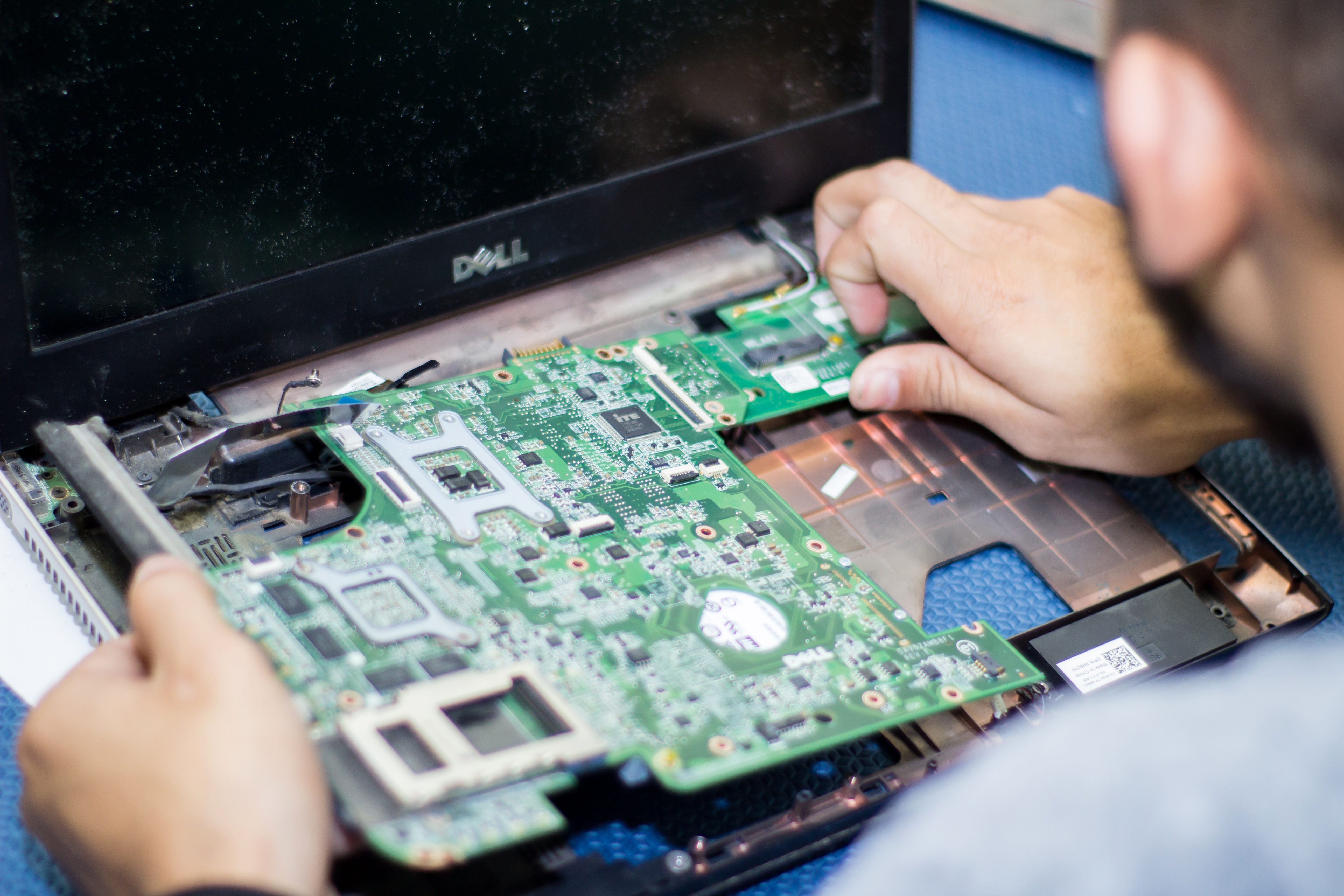 Homem abrindo um notebook, mostrando a placa e seus componentes.