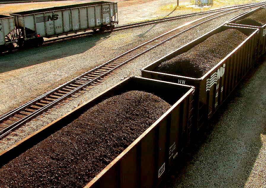 Vagões de trem marrons, cheios de minério preto de carvão.