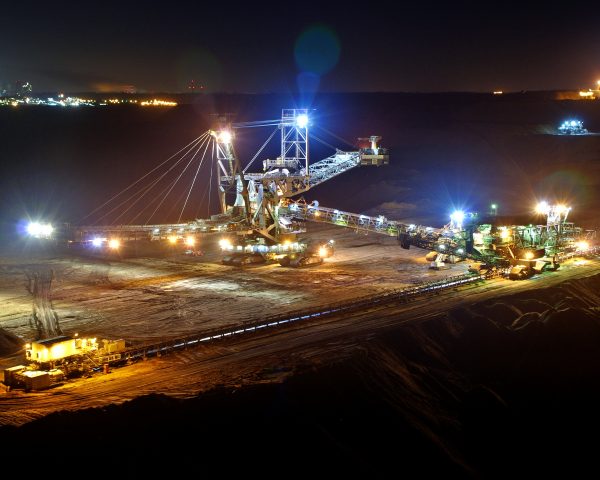 Imagem mostrando um grande guindaste e escavadeiras, todos utilizados para extrair carvão. Está de noite e existem luzes acesas nas máquinas.