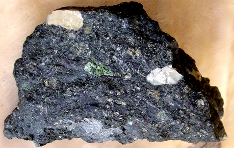 Uma rocha negra com intrusões claras e esverdeadas