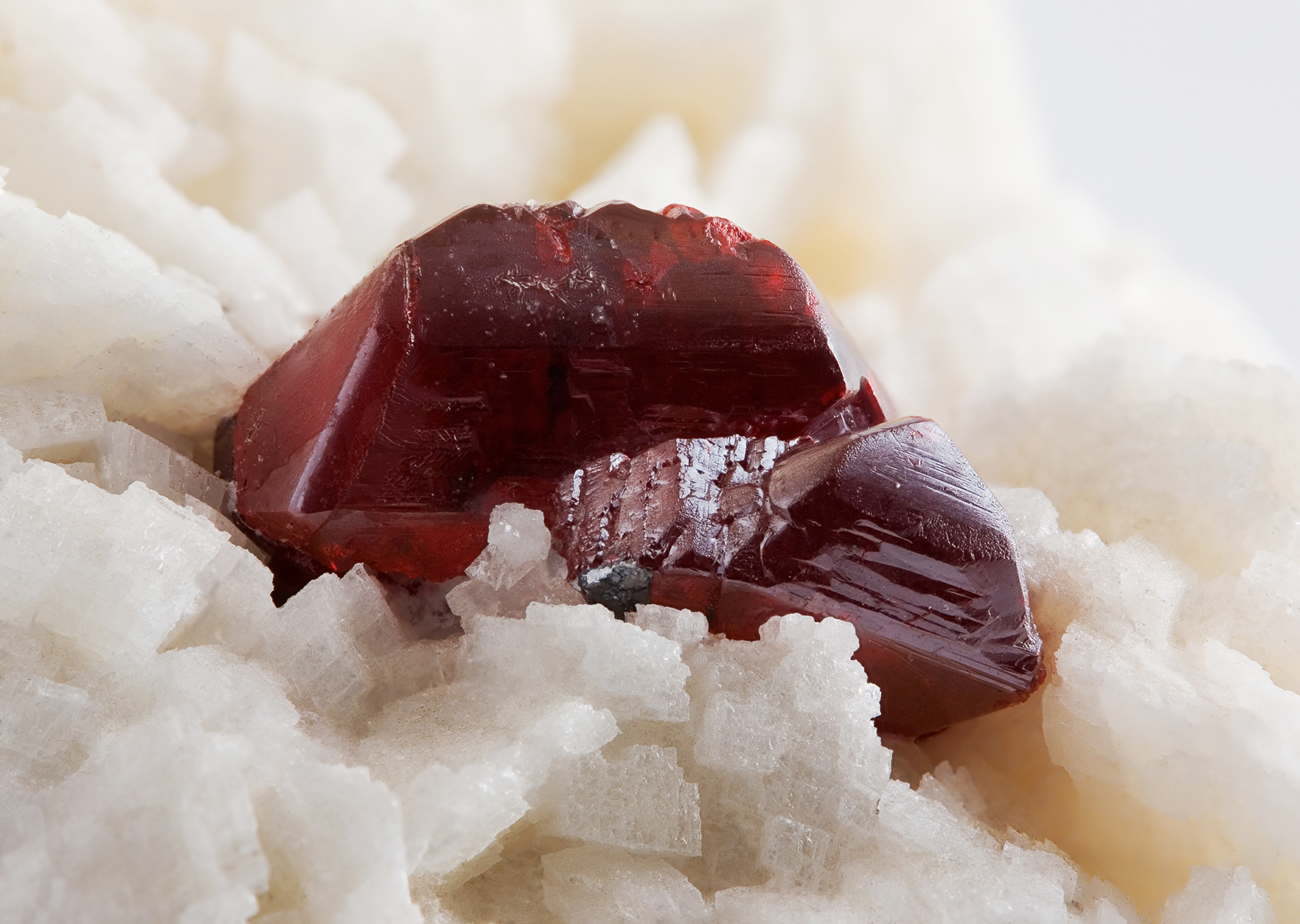 Mineral vermelho (cinábrio, de onde se extrai o mercúrio), com faces triangulares, no centro da foto. Ele está acompanhado de um mineral branco (matriz).