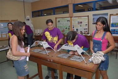 Exemplo de divulgação geocientífica: mostra de profissões na UFMG. Alunos utilizam estereoscópio, o aparelho permite ver o relevo nas fotografias. Muito utilizados por geólogos na confecção de mapas.